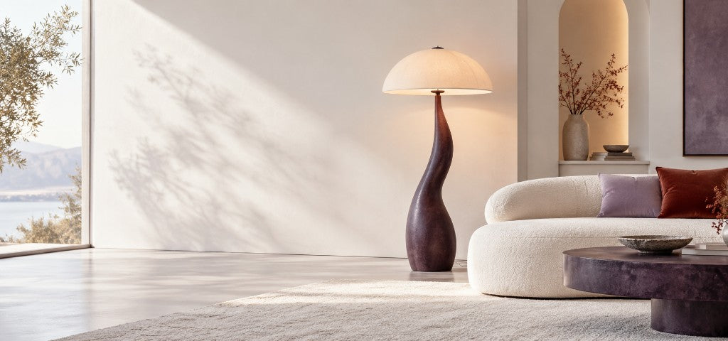 Sculptural floor lamp with a dome shade beside a curved cream sofa in a sunlit living room